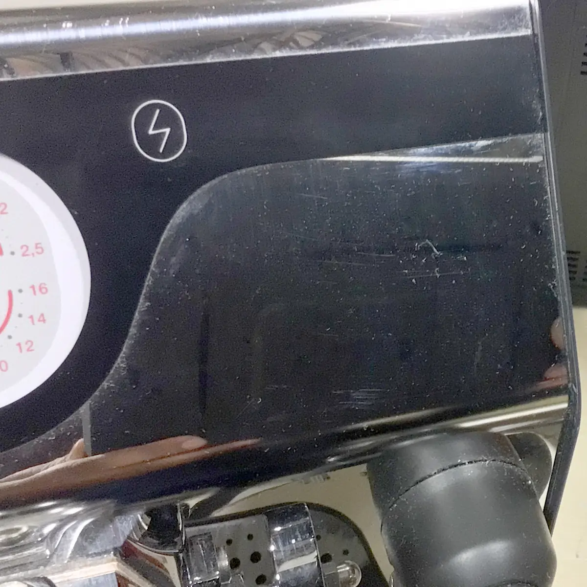 Close-up of the SIDEWALK SALE - VBM Domobar Super Analogic HX Espresso Machine OPEN BOX (E013), featuring part of a pressure gauge on the left and a power symbol above a scratched metallic surface.
