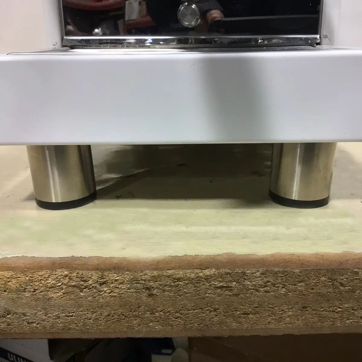 A SOLD RETURNED & REFURBISHED Bezzera Aria HX Special Edition Espresso Machine w/ Flow Control (C104) stands on metal cylinder legs atop a rough, unfinished wooden surface, with part of its countertop overhanging the legs.