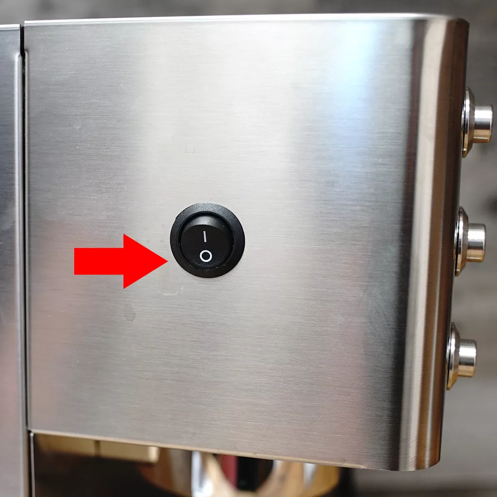 A close-up of a metallic appliance featuring a black power switch with I (on) and O (off) symbols, highlighted by a red arrow pointing to the switch. © 2025 1st-line.com