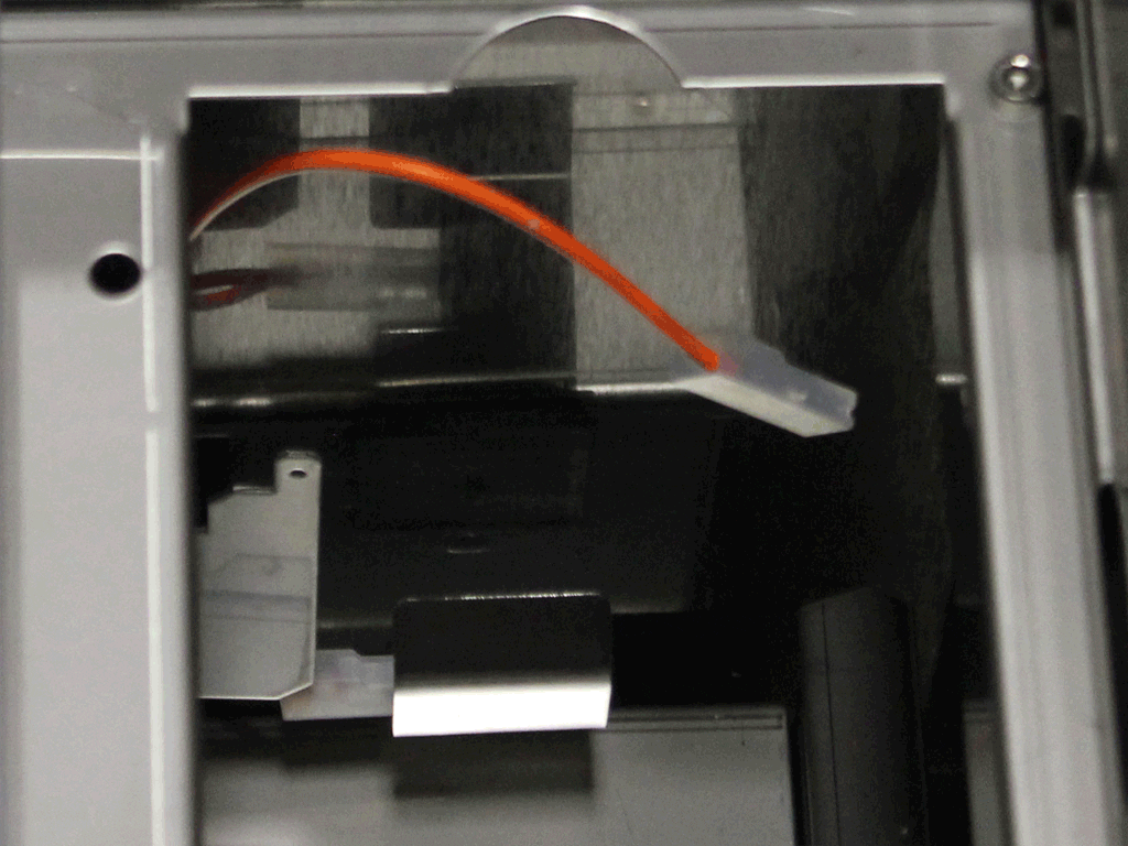 A close-up view of the inside of a computer case showing an orange SATA cable connected to a white plastic connector, alongside metallic and plastic components—ideal for illustrating a Tank to Direct Connect Conversion setup. 2025 1st-line.com