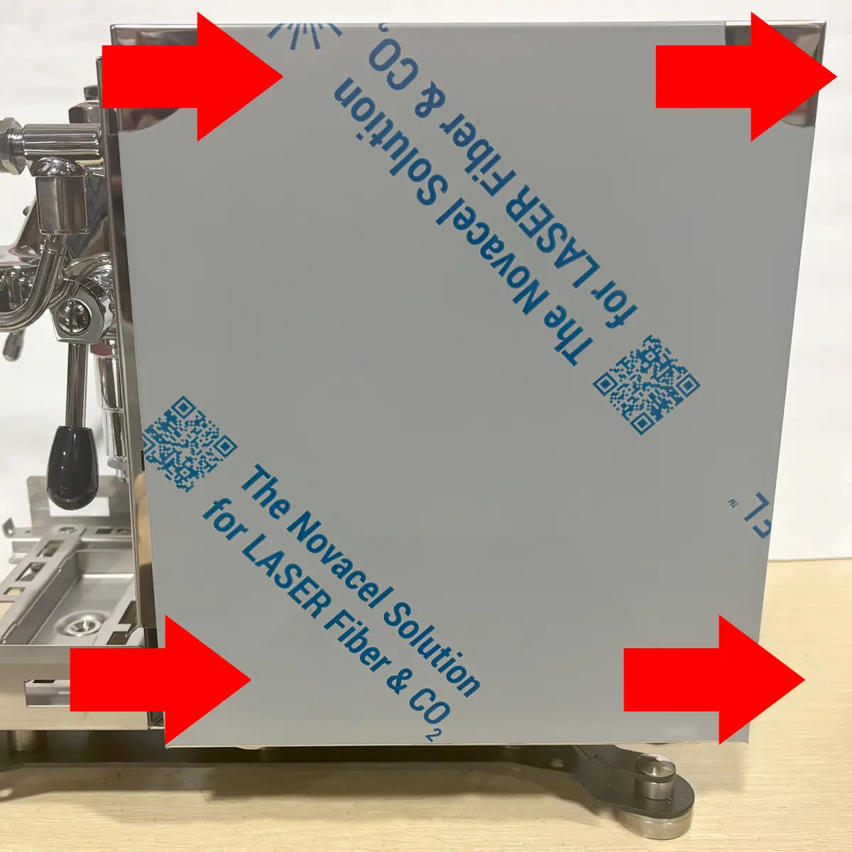 A metal panel with protective film, partially attached to an espresso machine—possibly a Bezzera Sole—is outlined by four large red arrows pointing at its edges. Text and QR codes are visible on the film, highlighting points of access.