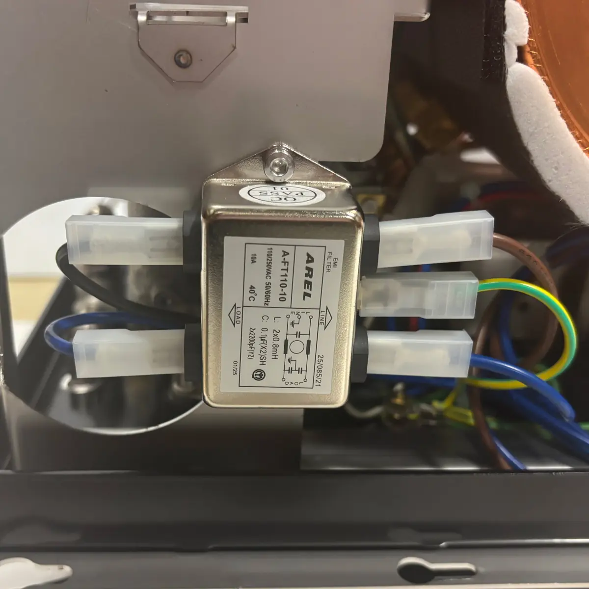 Close-up of an electrical component labeled “AREE AF1T51110C” with wires connected to its terminals, inside a machine with visible colored wiring in the background.