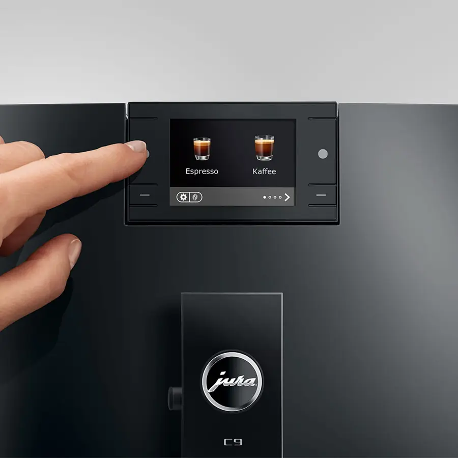 A hand selects Espresso or Kaffee on the Jura C9 Super-Automatic Espresso Machine’s touchscreen, highlighting its sleek black design and advanced features.