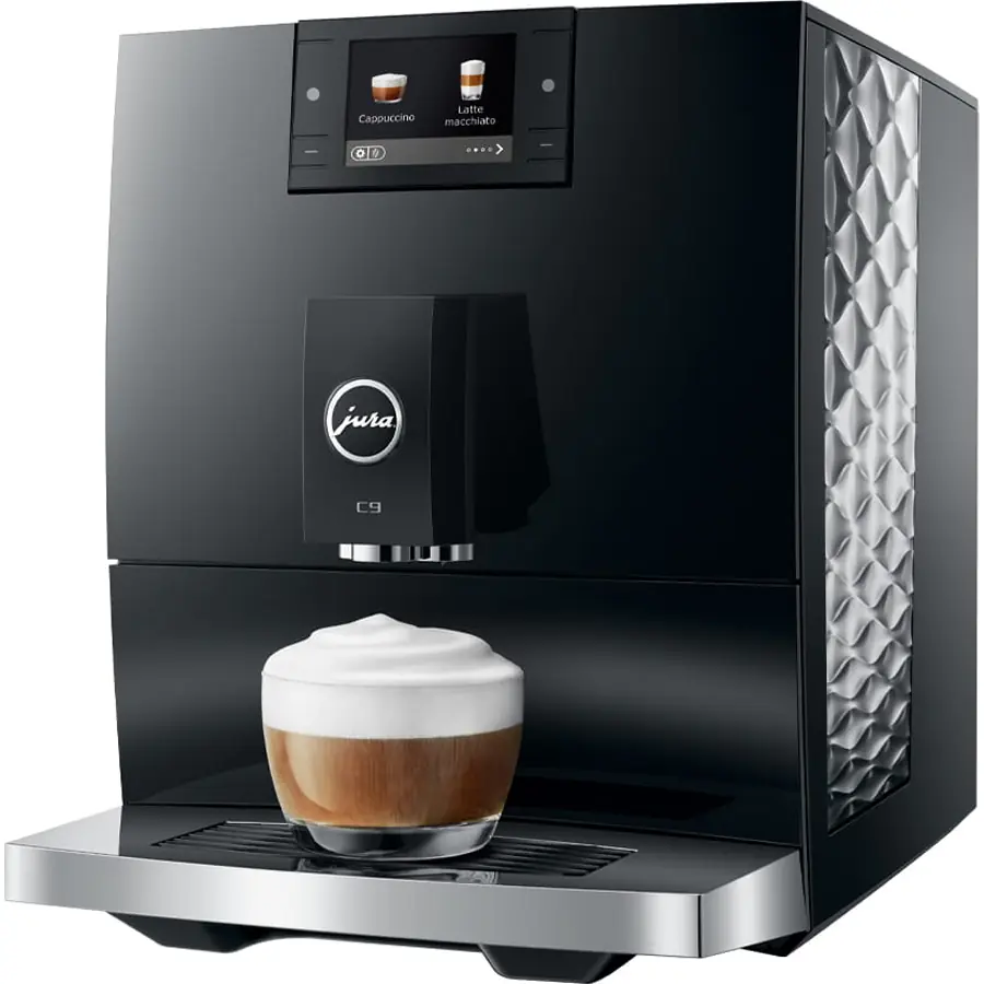 A Jura C9 Super-Automatic Espresso Machine brews a cappuccino, filling a clear glass with coffee topped by frothy milk on the drip tray.
