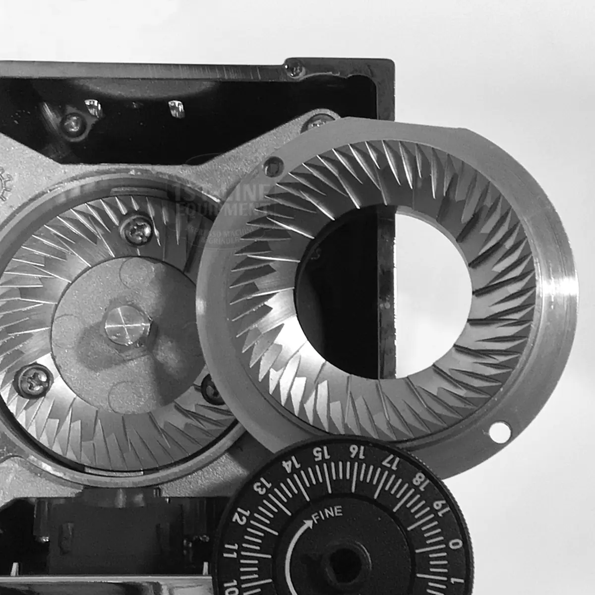 A close-up of the open Eureka Mignon Single Dose Pro Espresso Coffee Grinder shows two sharp, circular burrs with angled teeth and a grind size dial at the bottom right. The image appears in black and white.
