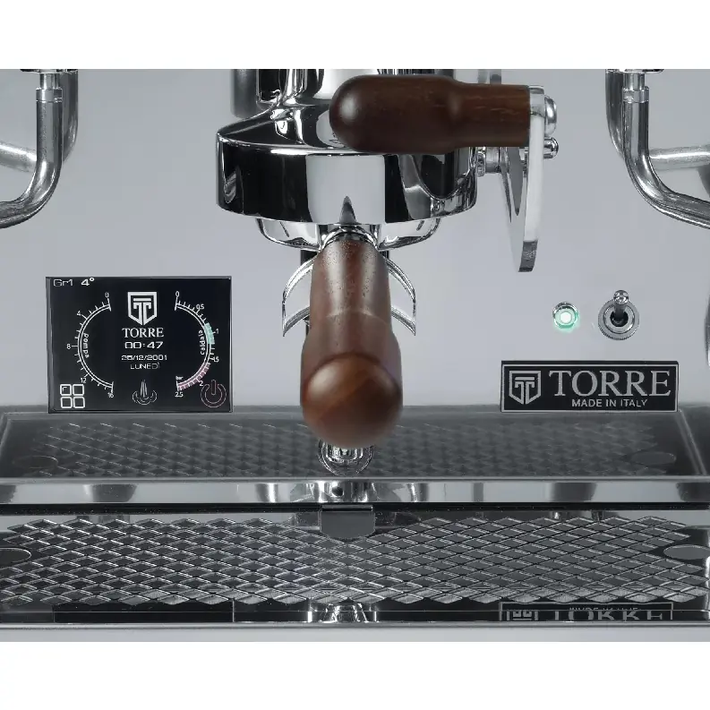 Close-up of the Torre Adele Dual Boiler Espresso Machine, showcasing its stainless steel body, wooden portafilter handle, digital display, and illuminated control buttons.