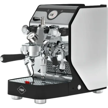 A modern Domobar Super espresso machine with a black and silver design, featuring flow control, multiple dials, levers, and a portafilter on a perforated metal drip tray. The VBM logo is visible on the front.