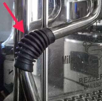 Close-up of a metal Strega espresso machine with a red arrow pointing to a black rubber grip covering the steam valve, highlighting where a potential steam valve leak may occur. 2025 1st-line.com