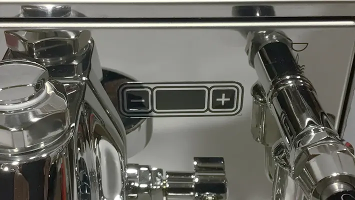 Close-up of the shiny metallic Bezzera Sole PID HX Espresso Machine, featuring a sleek black and white control panel with minus and plus symbols for precise adjustments.