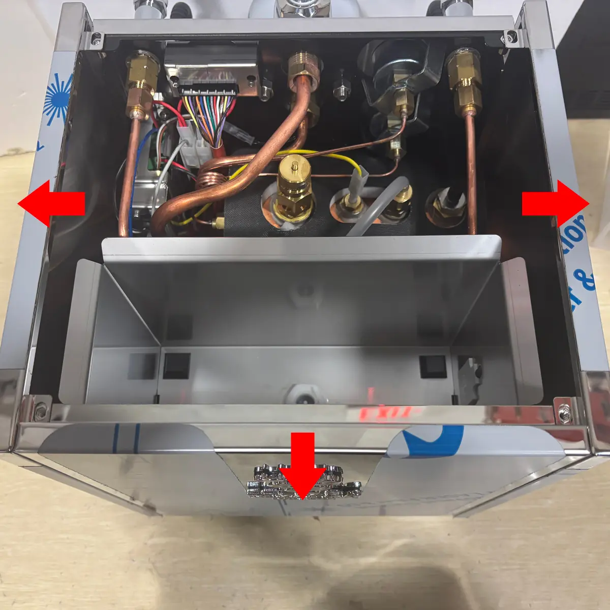 Top view of a Bezzera Sole metallic box with exposed wires and copper pipes inside; three red arrows point to key components, highlighting areas for accessing the inside of the device.