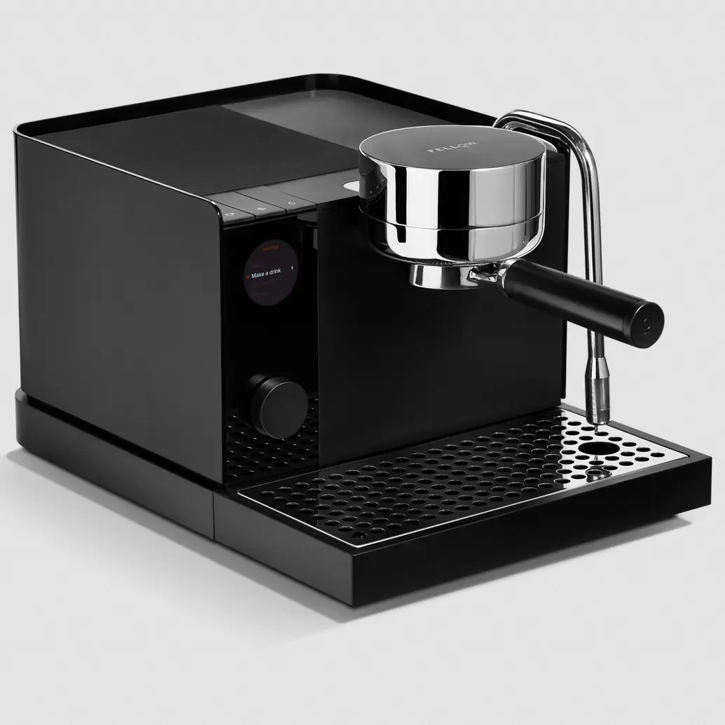 The Fellow Espresso Series 1 Espresso Machine, featuring a digital display, round portafilter handle, and metal steam wand, rests on a perforated drip tray against a light gray background.